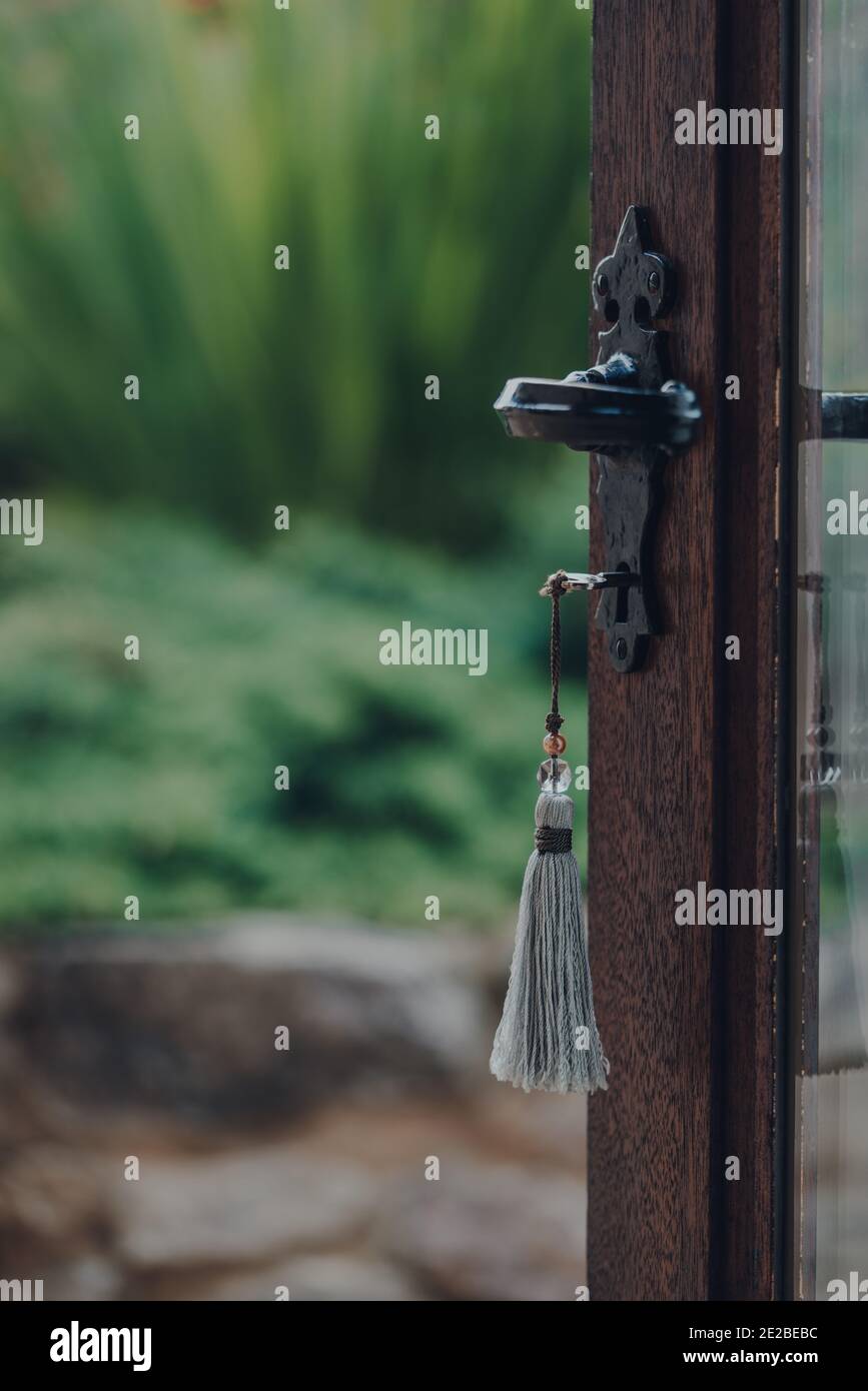 Schlüssel mit Quaste Schlüsselring in der offenen Tür, die zum Garten führt, selektiver Fokus. Stockfoto