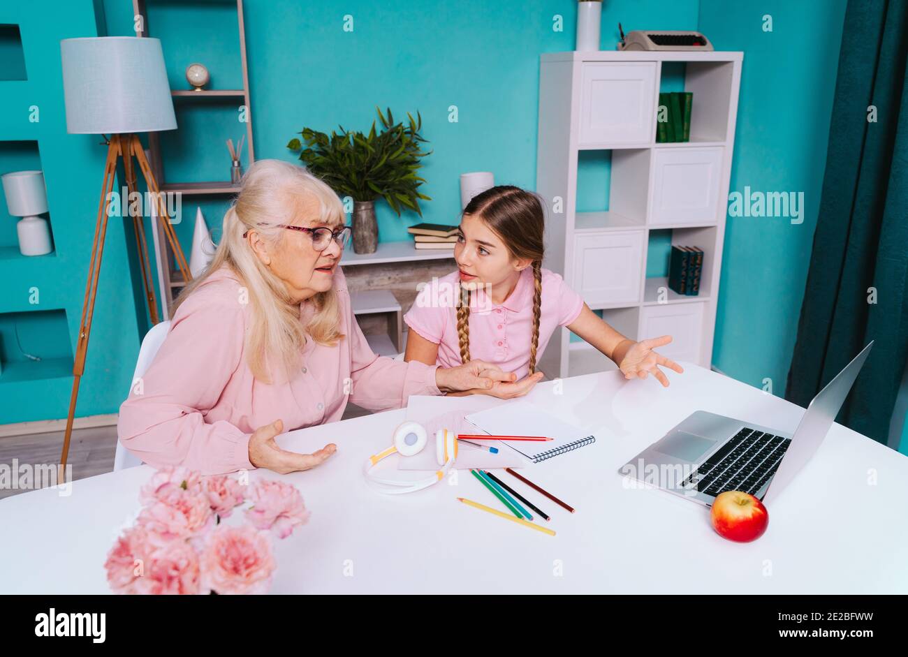 Filmisches Bild einer Großmutter und einer Enkelin, die zusammen Hausarbeiten machen. Mutter, die dem Kind hilft, das von zu Hause studiert, während 2020 die Sperre Stockfoto