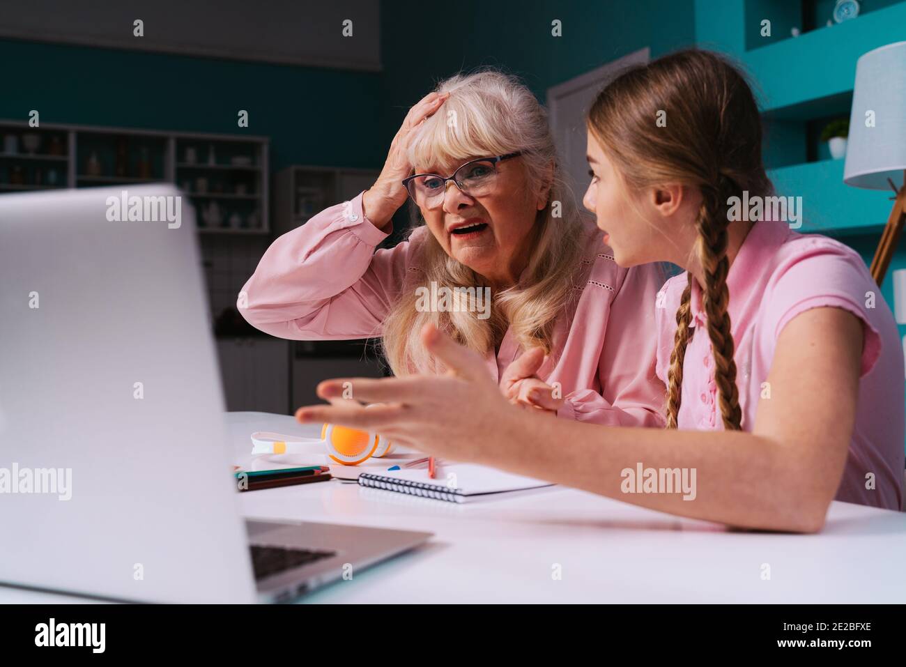 Filmisches Bild einer Großmutter und einer Enkelin, die zusammen Hausarbeiten machen. Mutter, die dem Kind hilft, das von zu Hause studiert, während 2020 die Sperre Stockfoto