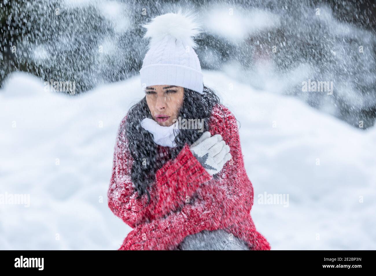 Frau zittert von Kälte während windigen verschneiten Wintertag im Freien trotz tragen warme Kleidung. Stockfoto