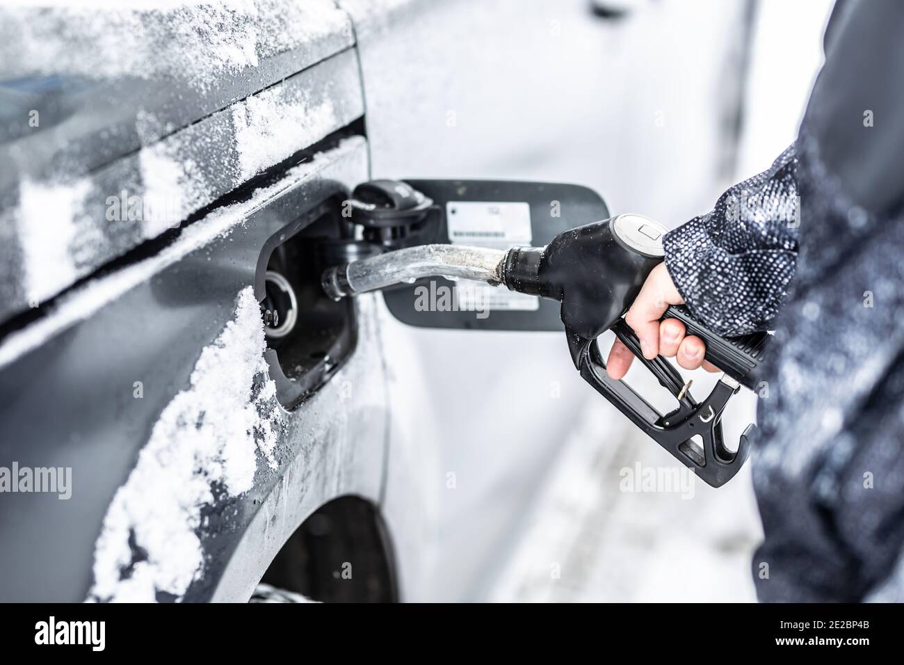 Hand eines Mannes, der während des eisigen Schneewetters den Tank seines Autos füllte. Stockfoto