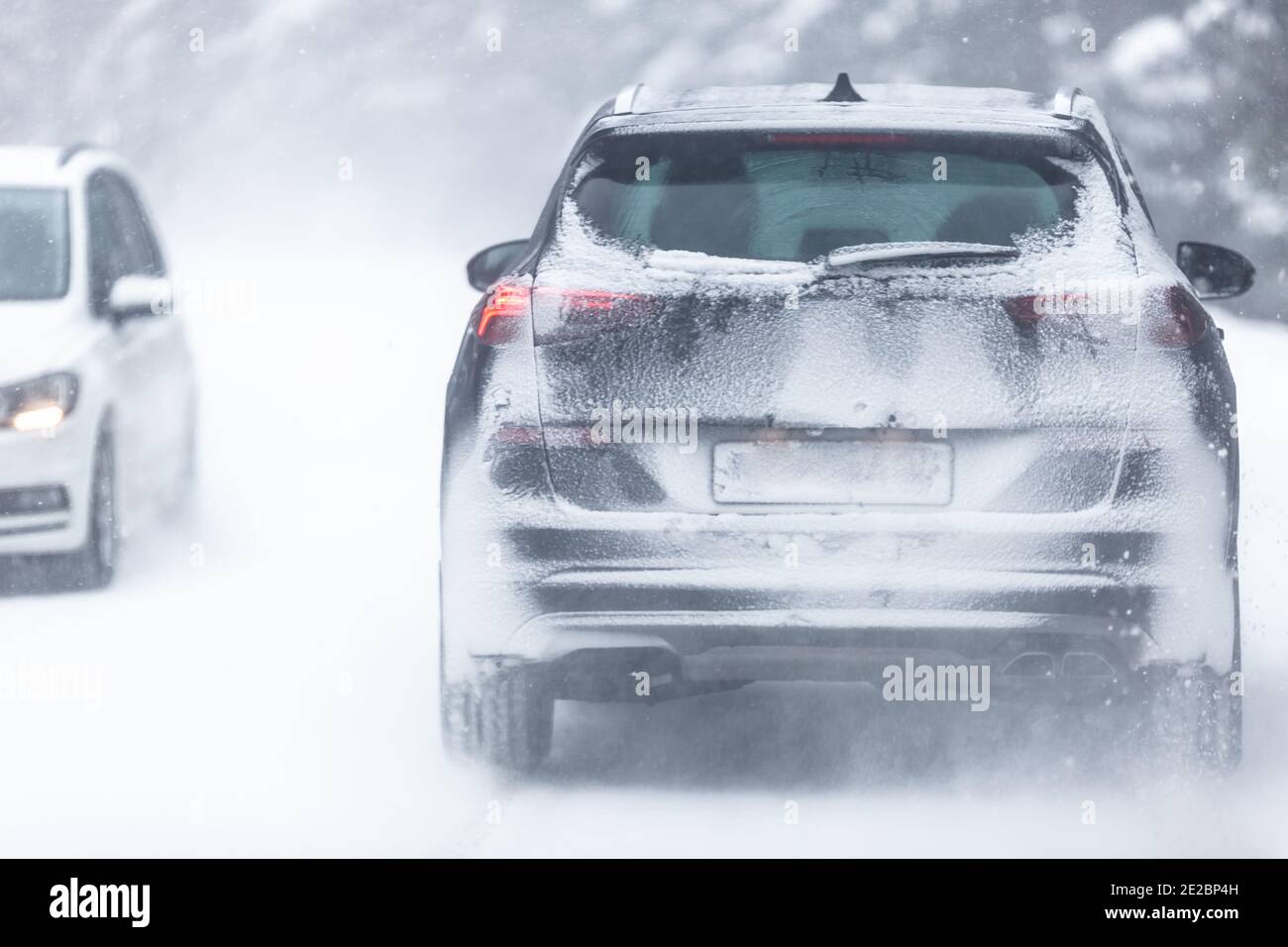 SUV-Auto fahren auf schneebedeckten rutschigen Straße im Wald, mit Kennzeichen unsichtbar aufgrund von Schnee. Stockfoto