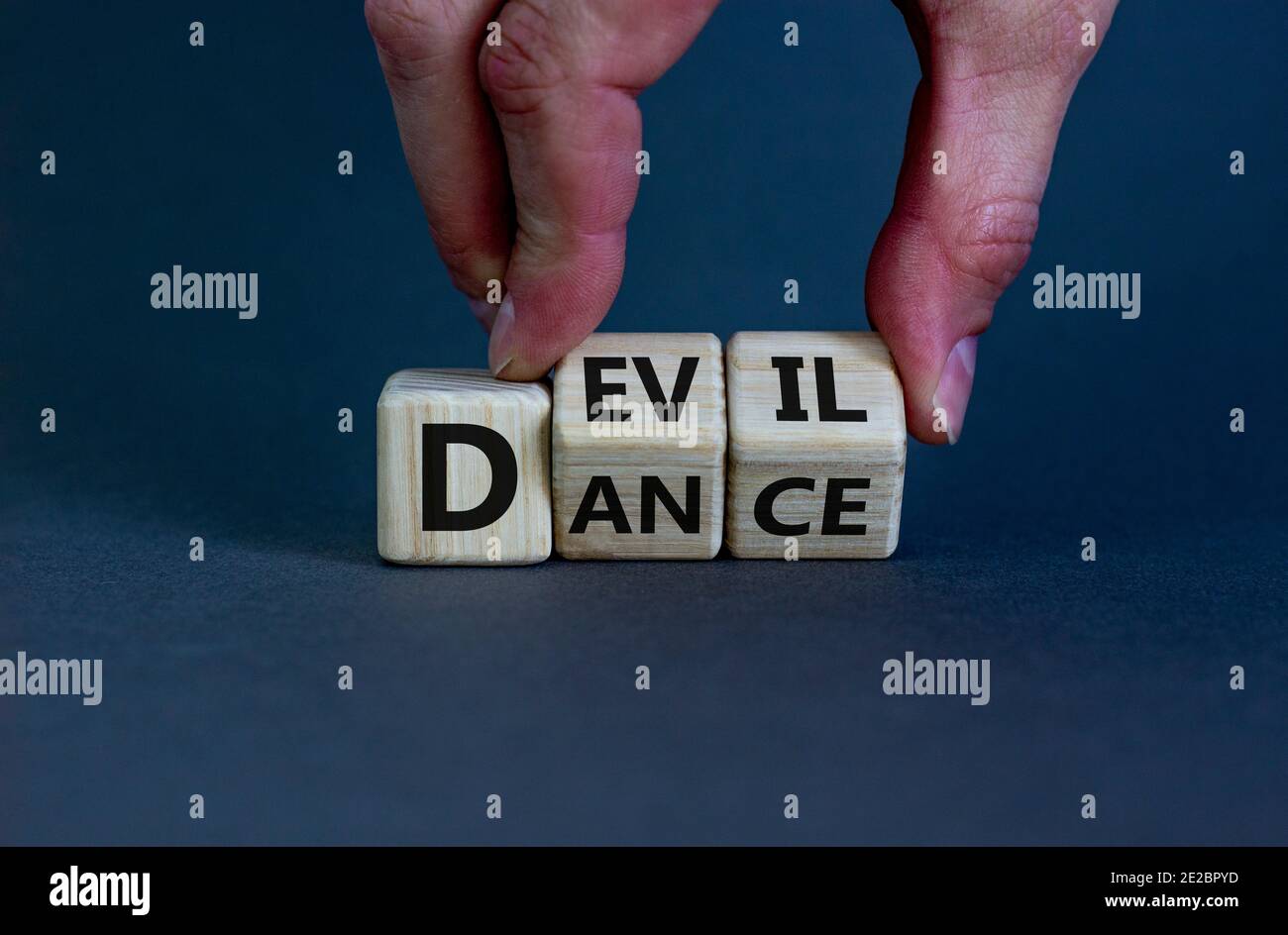 Tanz mit dem Teufel Symbol. Hand dreht Würfel und ändert das Wort 'dance' in 'dil'. Schöner grauer Hintergrund. Business und Tanz mit Teufel immora Stockfoto