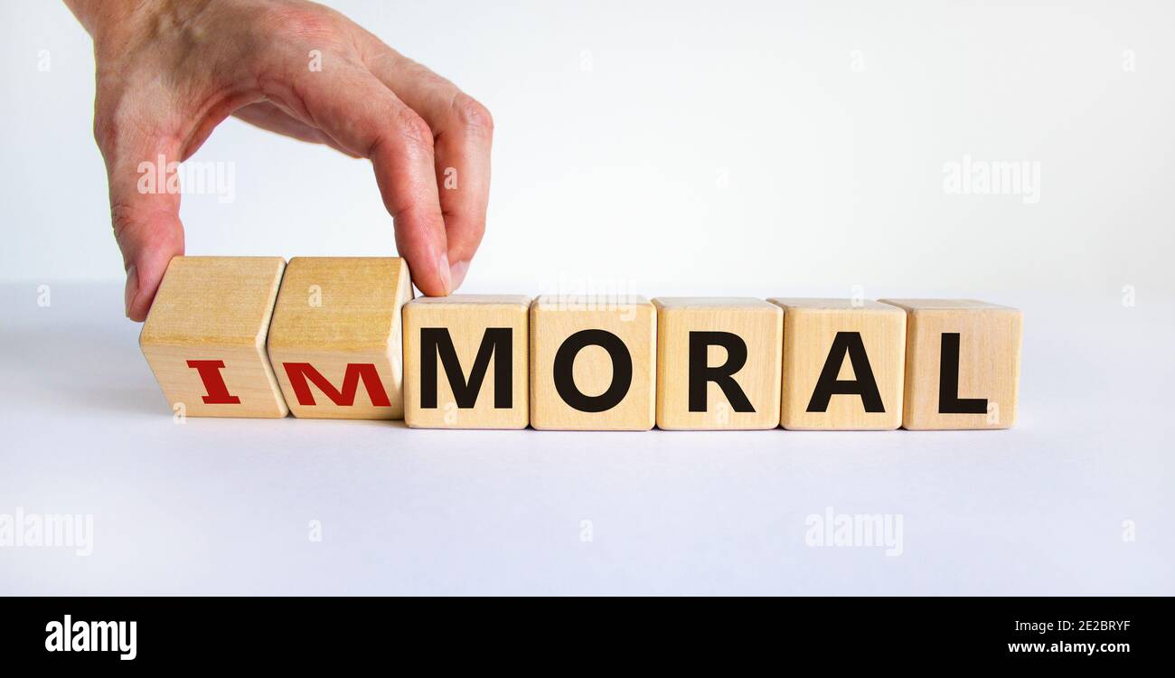 Moralisches oder unmoralisches Symbol. Hand dreht Würfel und ändert das Wort "unmoralisch" in "oral". Schöner weißer Hintergrund. Business und moralische oder unmoralische Konzept Stockfoto