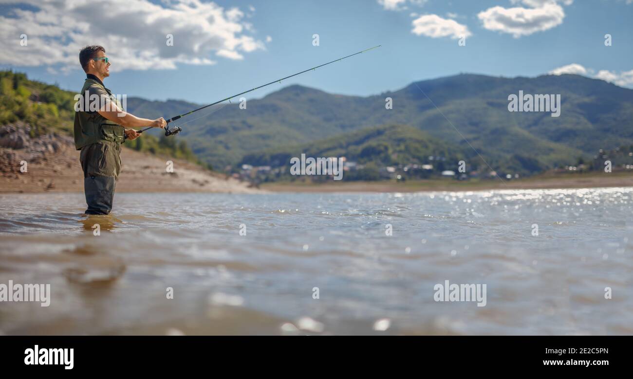 Junger Mann, der auf einem See in Mavrovo, Mazedonien angeln soll Stockfoto