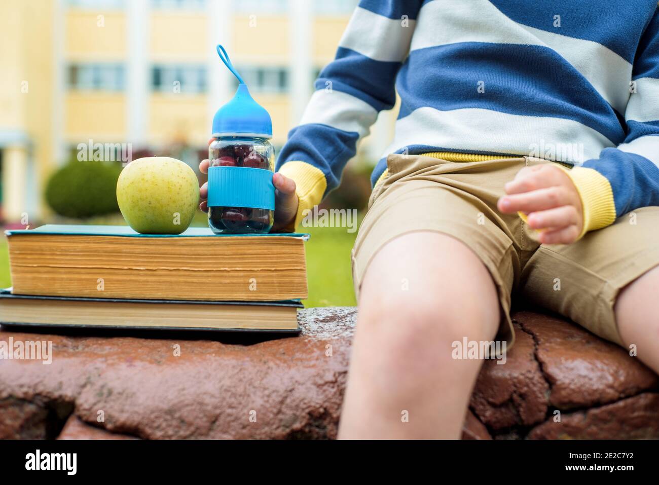 Mittagspause in der Schule.EIN Junge im Schulhof isst frisches Obst und Gemüse. Wechsel im Freien. Stockfoto