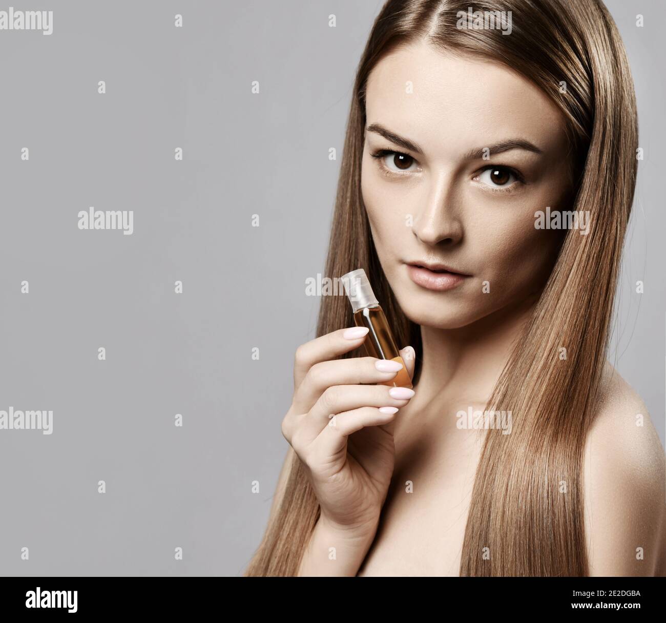 Profil der jungen Frau mit langen seidig geraden Haar halten Flasche mit Moistirizing Öl für die Haarrehabilitation oder Behandlung Stockfoto