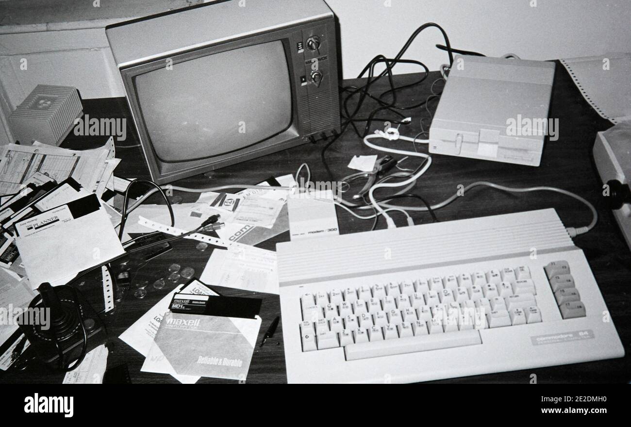 Eine schlampige Arbeitsstation in den 1980er Jahren, mit einem Commodore 64 Computer, der an einen schwarz-weißen Fernseher angeschlossen ist, einem 5 1/4 Zoll Diskettenlaufwerk, einem 300 Baud Modem und einem Punktmatrix-Drucker Stockfoto