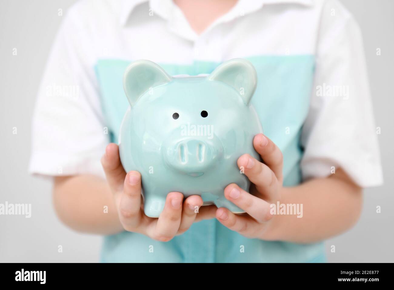 Kind hält Sparschwein. Sparkonzept Stockfoto