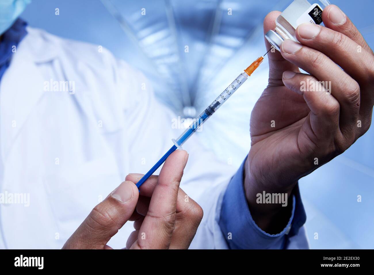 Nahaufnahme des afroamerikanischen Wissenschaftlers, der im Labor mit Spritze und Glasfläschchen mit Flüssigimpfstoff interagiert. Stockfoto