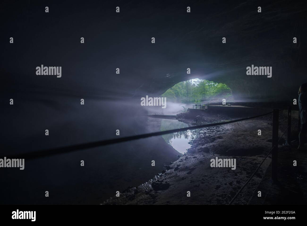 Ausgang einer dunklen Höhle mit unterirdischem Fluss und einigen Nebel Stockfoto