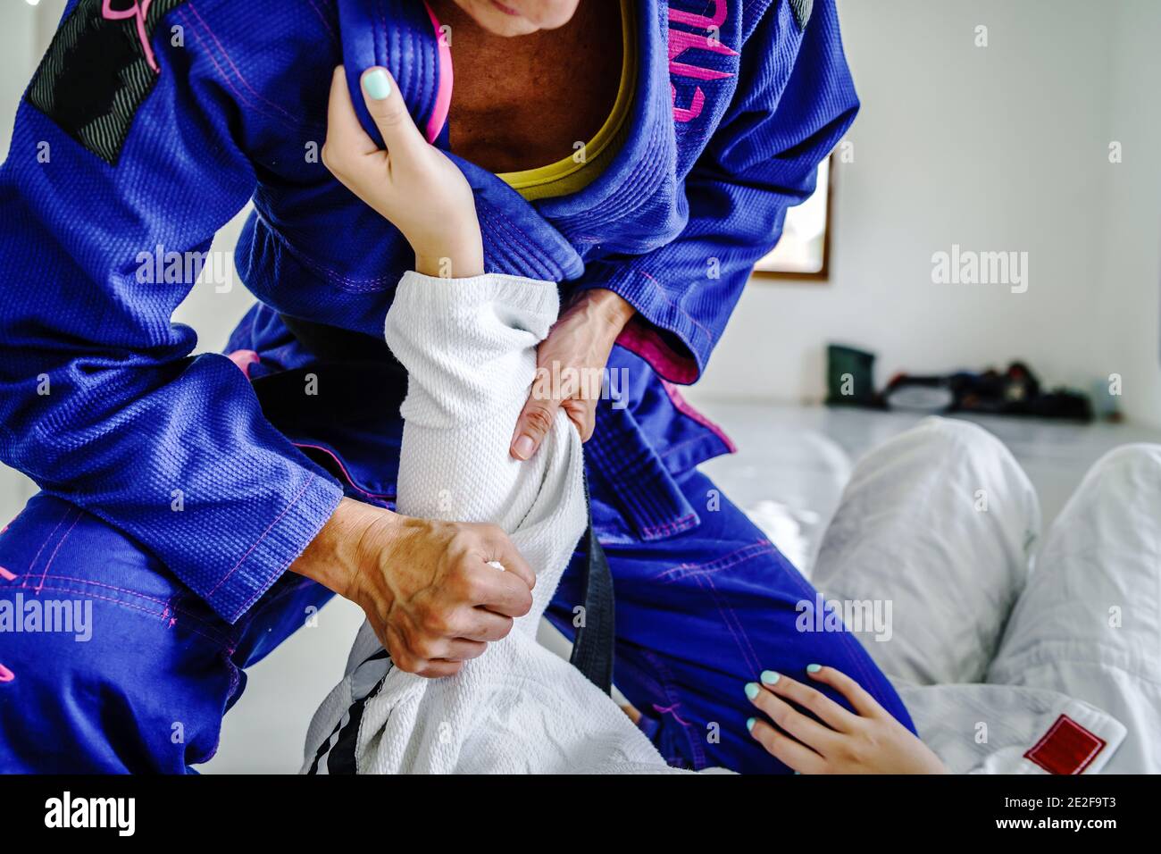 Griffe von der Wache in brasilianischen Jiu jitsu bjj oder judo Training Sparring zwei weibliche Athleten Kämpfer Bohrtechniken Für den Wettbewerb A Stockfoto