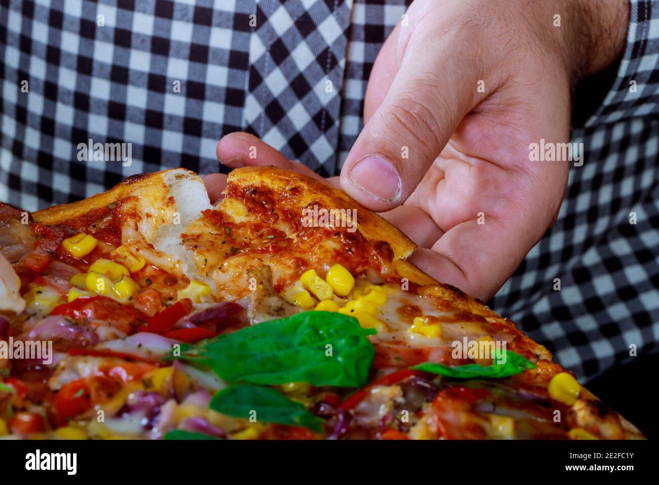 Hand Kommissionierung lecker ein Stück hausgemachte Pizza liegen auf Tabelle Stockfoto