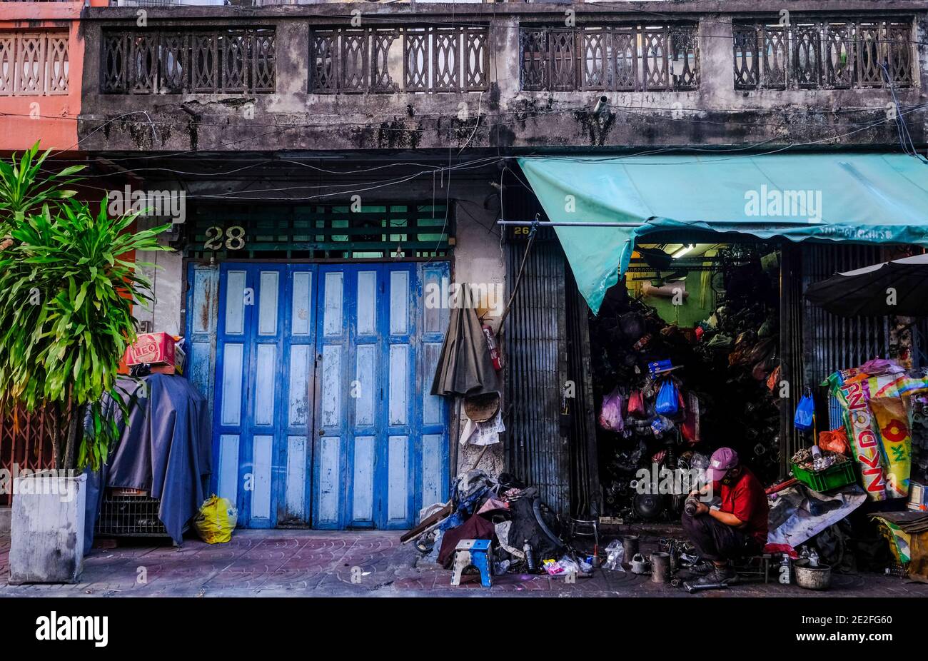 Ein Mann arbeitet außerhalb seiner Werkstatt in Talat Noi, Bangkok, Thailand Stockfoto