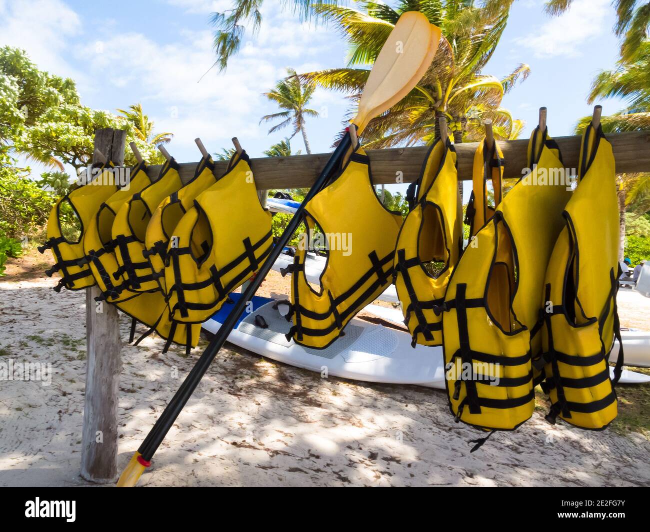 Gelbe Schwimmwesten oder Schwimmwesten, die auf einem hölzernen hängen Pole an einem tropischen weißen Sandstrand auf der Insel Von Mauritius Konzept Erholung oder Sport Stockfoto