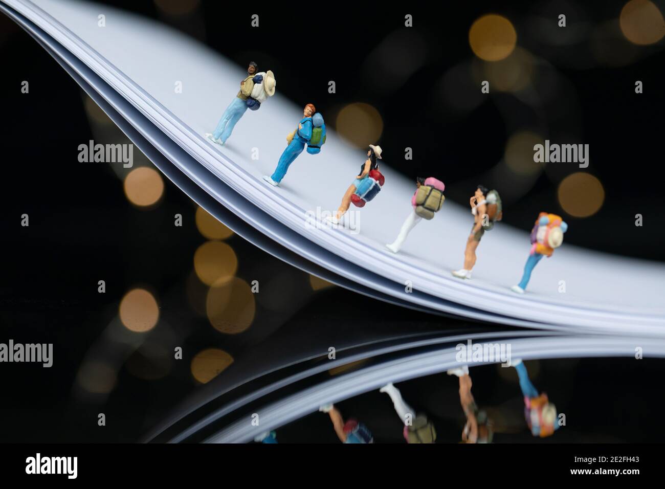 Selektive Fokus Aufnahme von niedlichen Reisenden Figuren auf einer Biegung Metalloberfläche mit Bokeh-Leuchten Stockfoto