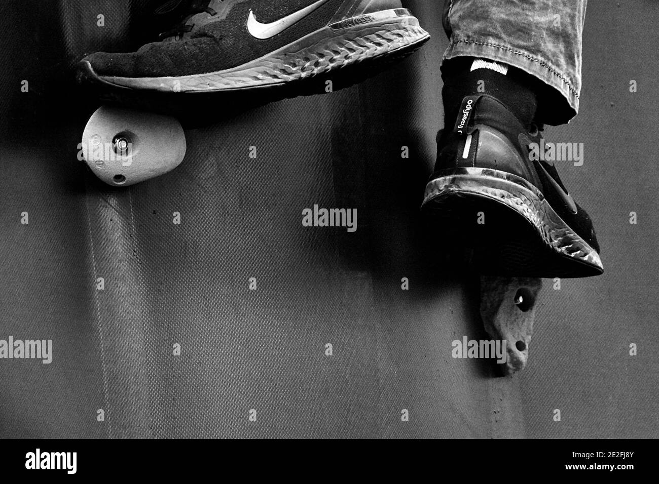 Braunschweig, 29. September 2019: Füße in Sneakers unterstützen an Kletterwand und schieben Sportler nach oben, Konzeptbild für Aufstieg und Anstrengung, schwarz A Stockfoto