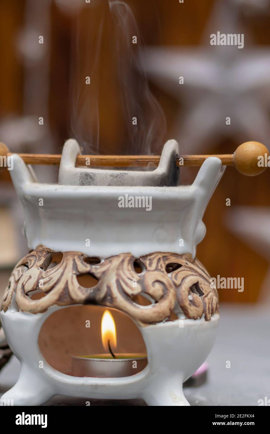 Aromatische Öllampe mit brennender Kerzenflamme und Dampf. Nahaufnahme, selektiver Fokus, Nebelansicht. Stockfoto