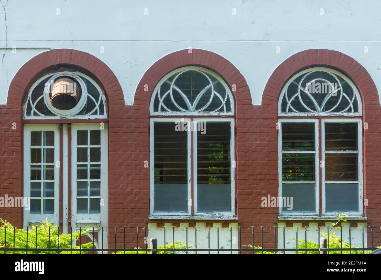 Drei alte Bogenfenster mit Holzrahmen. Die Fassade und die Fensterläden sind mit geschälter alter Farbe gestrichen. Retro-Fenster in der Architektur des letzten Jahrhunderts. Selektiver Fokus, b Stockfoto Drei alte Bogenfenster mit Holzrahmen. Die Fassade und die Fensterläden sind mit geschälter alter Farbe gestrichen. Retro-Fenster in der Architektur des letzten Jahrhunderts. Selektiver Fokus, b Stockfoto