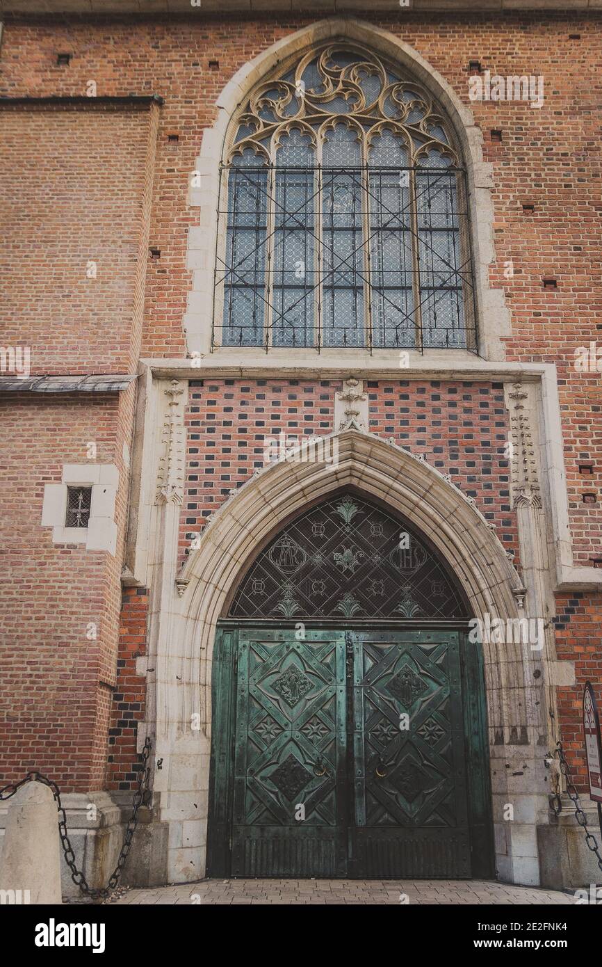 Zweiblättrige Metalltür unter einem halbrunden Bogen aus Stein mit Ein wunderschönes Fenster Stockfoto