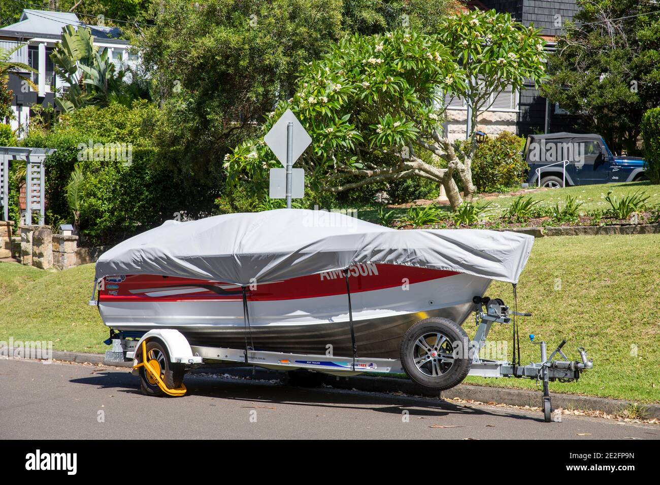 Boot auf einem Anhänger in einer Sydney Straße hat ein Schutzabdeckung, um es sauber zu halten, und ein gelbes Rad Schloss für Sicherheit, Sydney, Australien Stockfoto