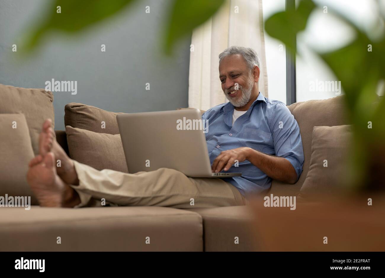 EIN ÄLTERER ERWACHSENER, DER GLÜCKLICH MIT SEINEM LAPTOP UNTERWEGS WAR Stockfoto