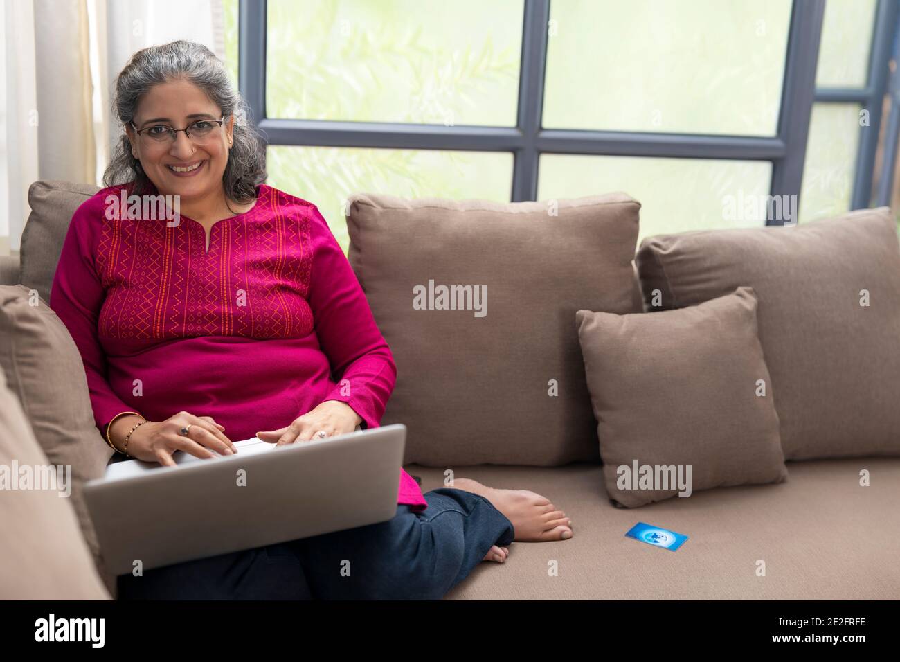 EINE GLÜCKLICHE FRAU, DIE BEIM BENUTZEN DER KAMERA LÄCHELT NOTEBOOK Stockfoto