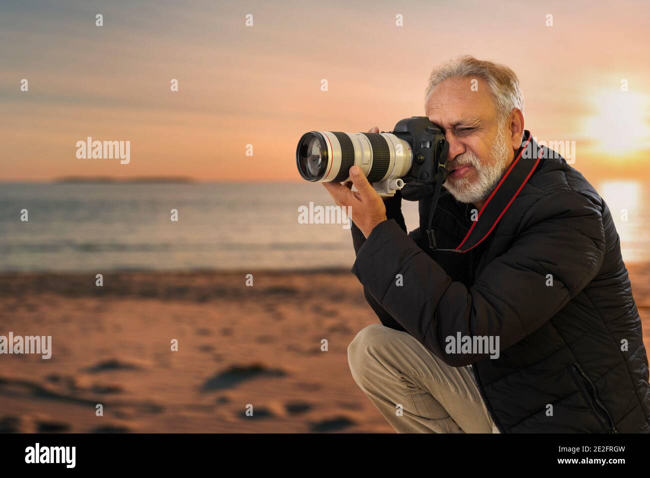 PORTRAIT EINES ÄLTEREN ERWACHSENEN MANNES, DER FOTOS AUF EINEM KLICKT STRAND Stockfoto