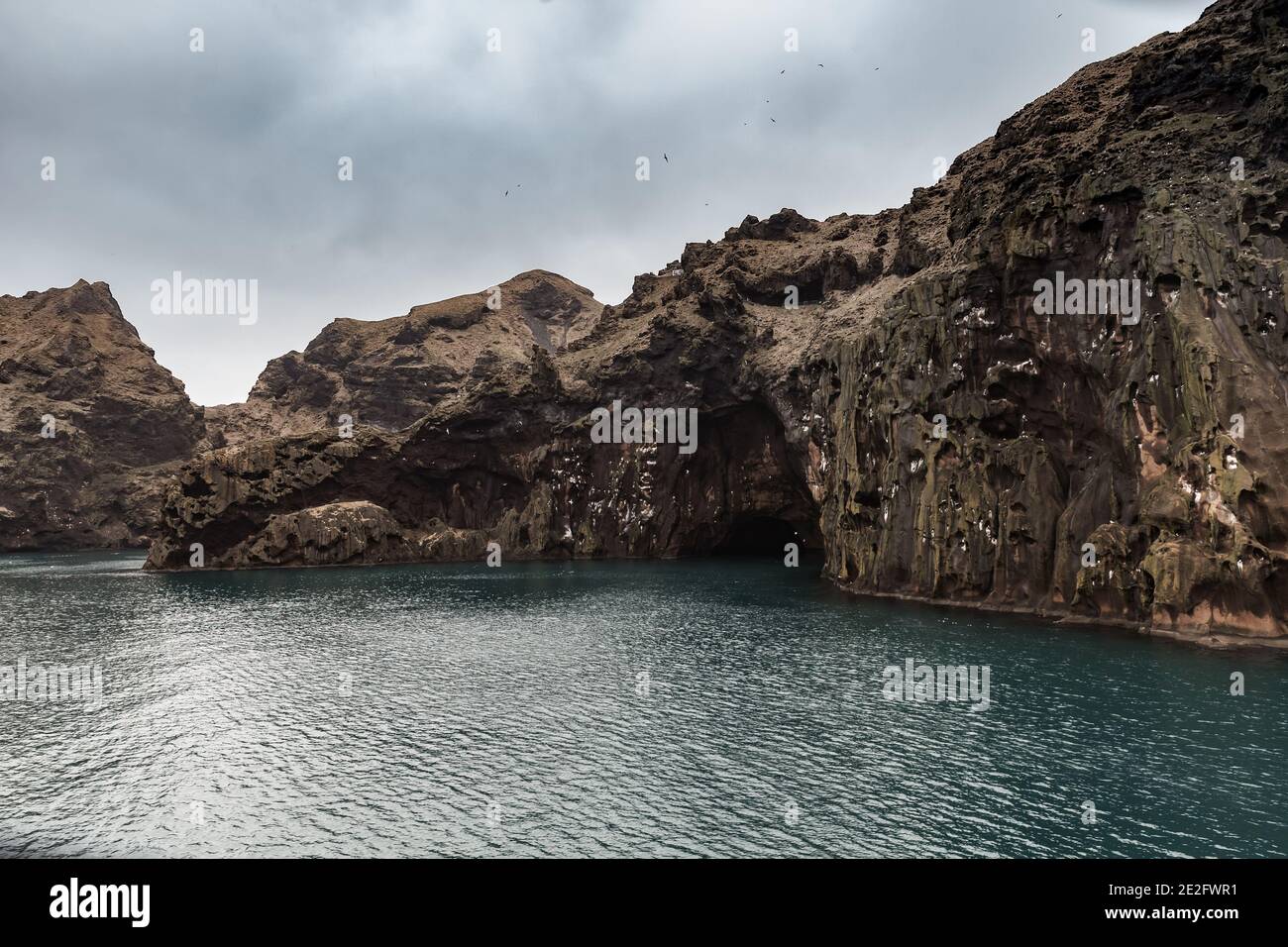 Dunkle Felsküsten der Insel Vestmannaeyjar, Island. Landschaftlich reizvolle Küstenlandschaft im Norden unter dunklem Himmel Stockfoto