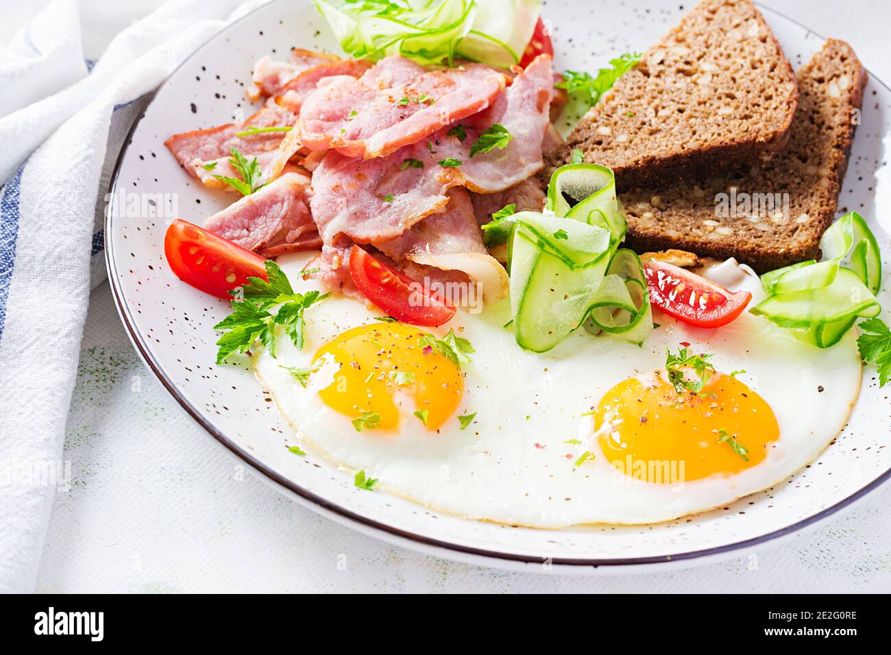 Englisches Frühstück - Spiegelei, Speck, Tomaten und Brot. Stockfoto