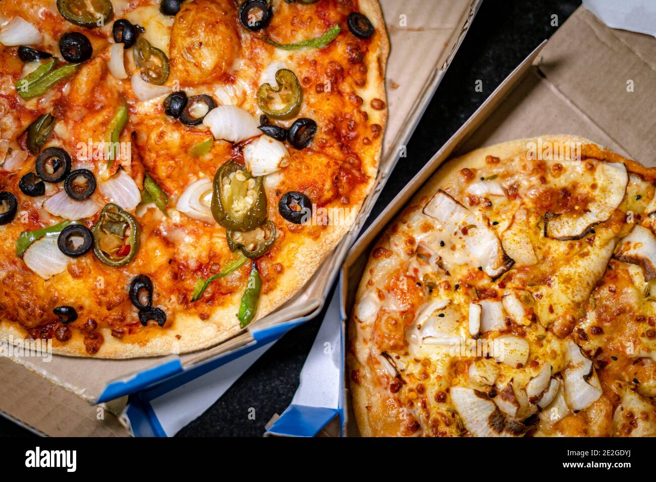 Blick von oben auf zwei verschiedene vegetarische Pizzas in den Takeout-Boxen Stockfoto