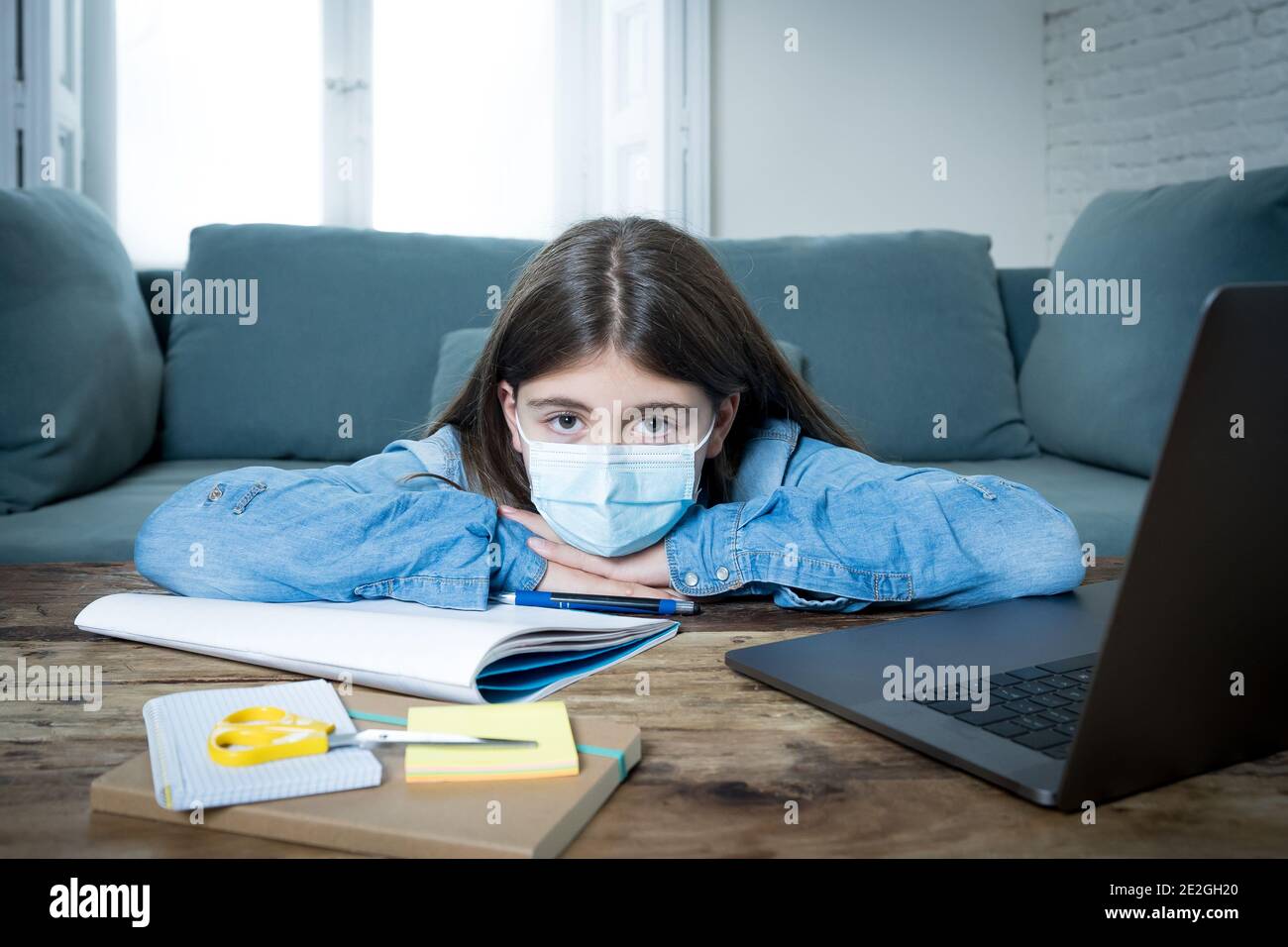 Gelangweilt und deprimiert Teenager-Mädchen mit Gesichtsmaske auf Laptop Studieren zu Hause in Online-Bildung Klasse als High School Wegen des neuen COVID-19 geschlossen bleiben Stockfoto