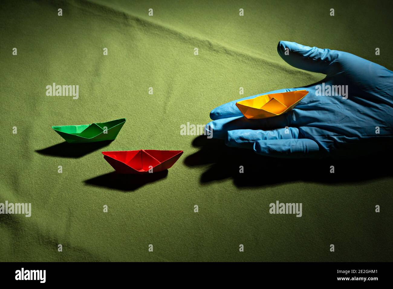 Hand in Schutzhandschuh hält Origami-Boot Stockfoto