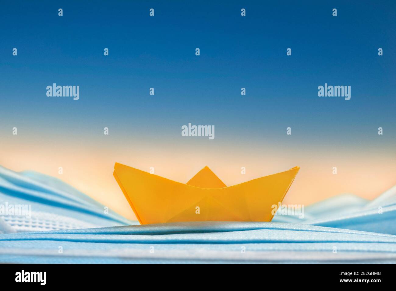 Gelbes Origami-Boot auf blauen Einweg-Gesichtsmaske Stockfoto