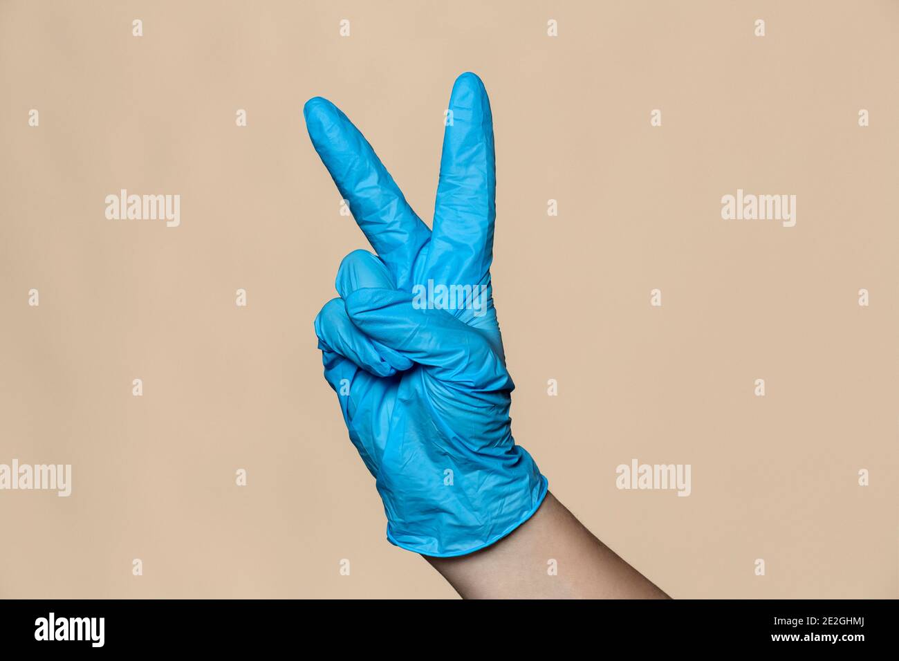 Hand in Schutzhandschuh gestikulieren Frieden Zeichen Stockfoto