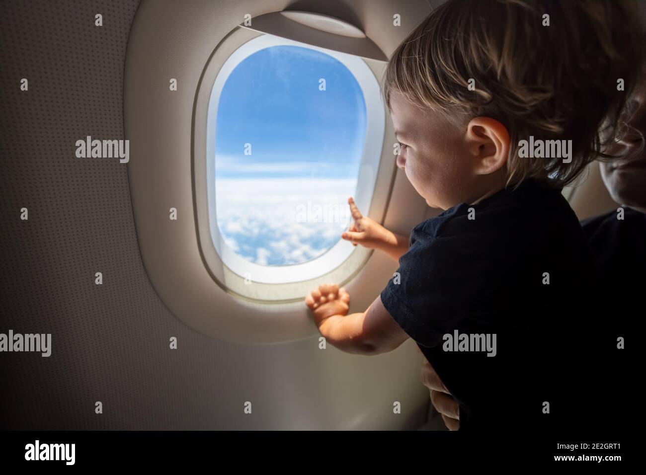 Nettes Kleinkind zeigt seinen Finger auf den Himmel durch das Fenster. First Flight Konzept, Reisen mit Kindern Stockfoto