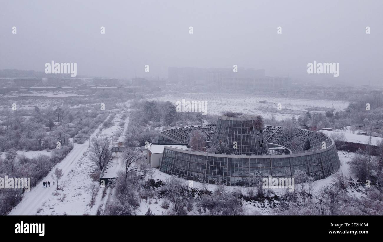 Altes verlassene Gewächshaus aus Sowjetzeiten mit sehr modernem futuristischem Design, das im alten Botanischen Park in Armenien mit Schnee bedeckt und vergessen wurde Stockfoto