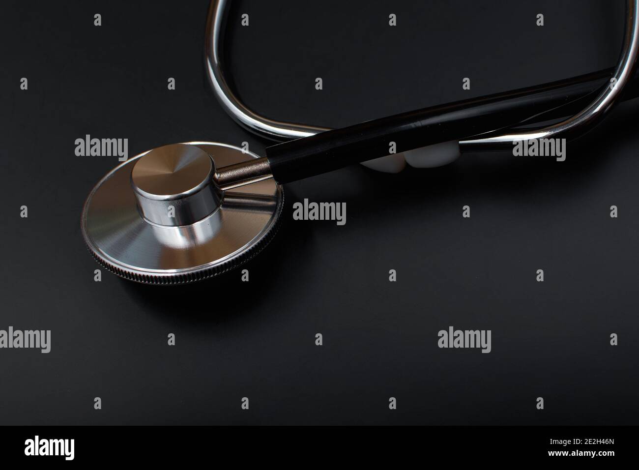 Stethoskop mit schwarzem Gummischlauch, auf schwarzem Hintergrund. Medizinisches Instrument für Therapeuten und Kardiologen. Ein Gerät zum Hören von Herz und Puls Stockfoto