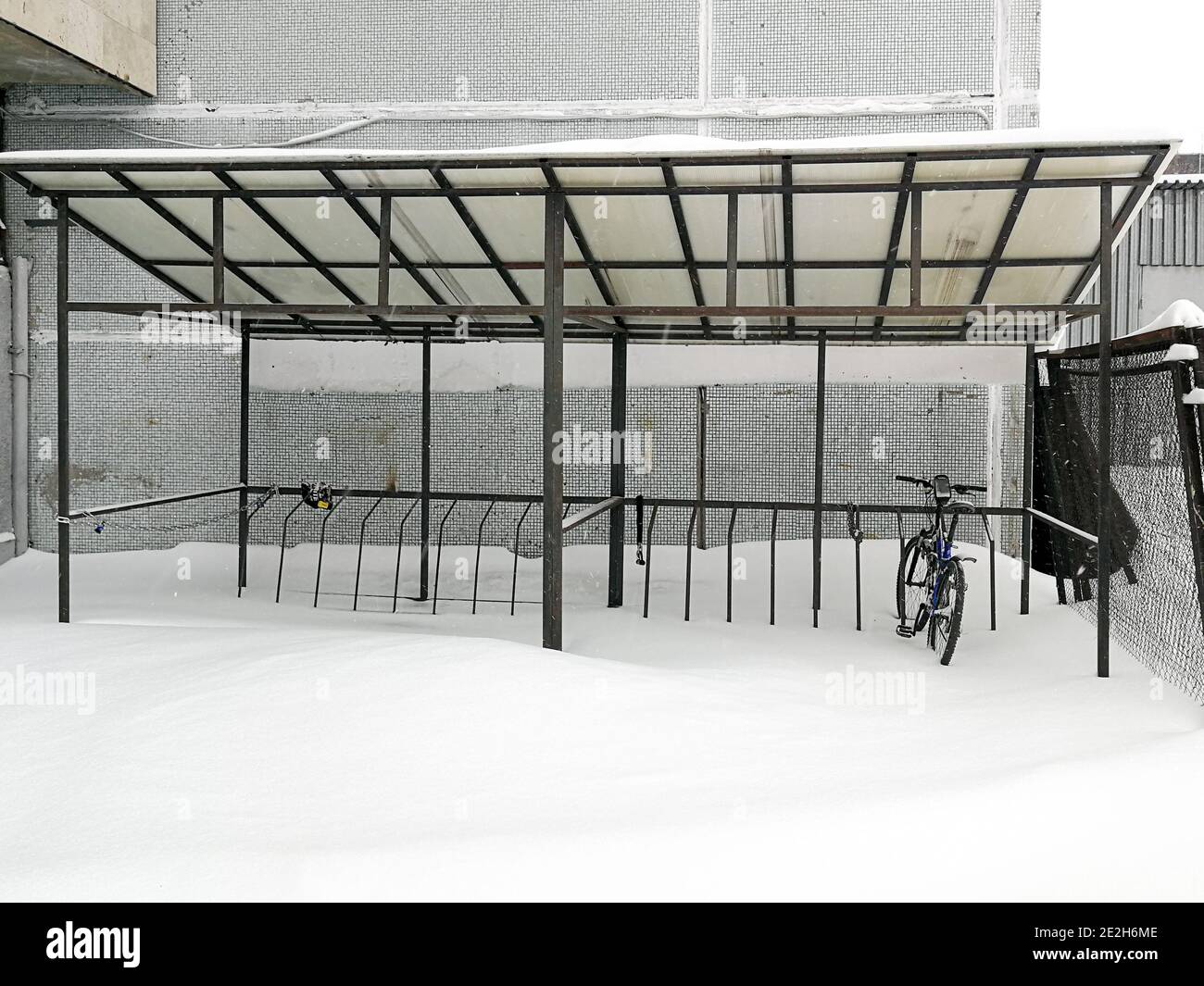 Einzelfahrrad im Bikeparkplatz im Winter. Ein ungewöhnlich starker Schneefall fegt über die Stadt. Schnee driftet herum. Stockfoto