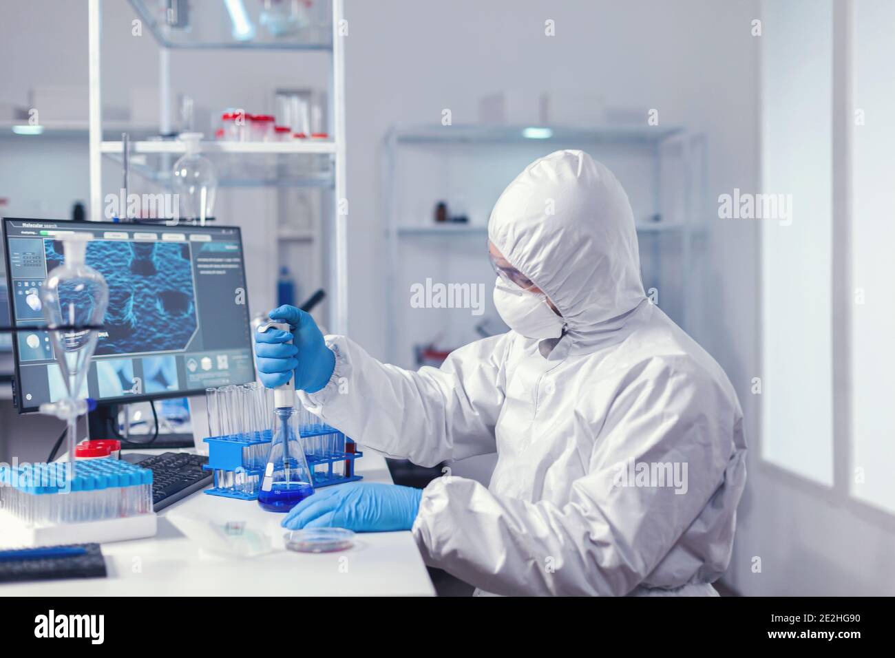 Arzt, der mit der automatischen Pipette arbeitet, die die Probe aus dem Reagenzglas entnimmt. Chemiker im modernen Labor Forschung mit Spender während der globalen Epidemie mit covid-19. Stockfoto