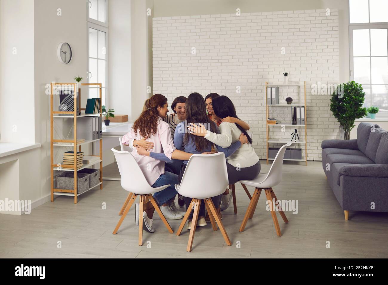 Glückliche Frauen sitzen im Kreis im Firmenbüro, reden und motivieren sich gegenseitig zum Erfolg Stockfoto