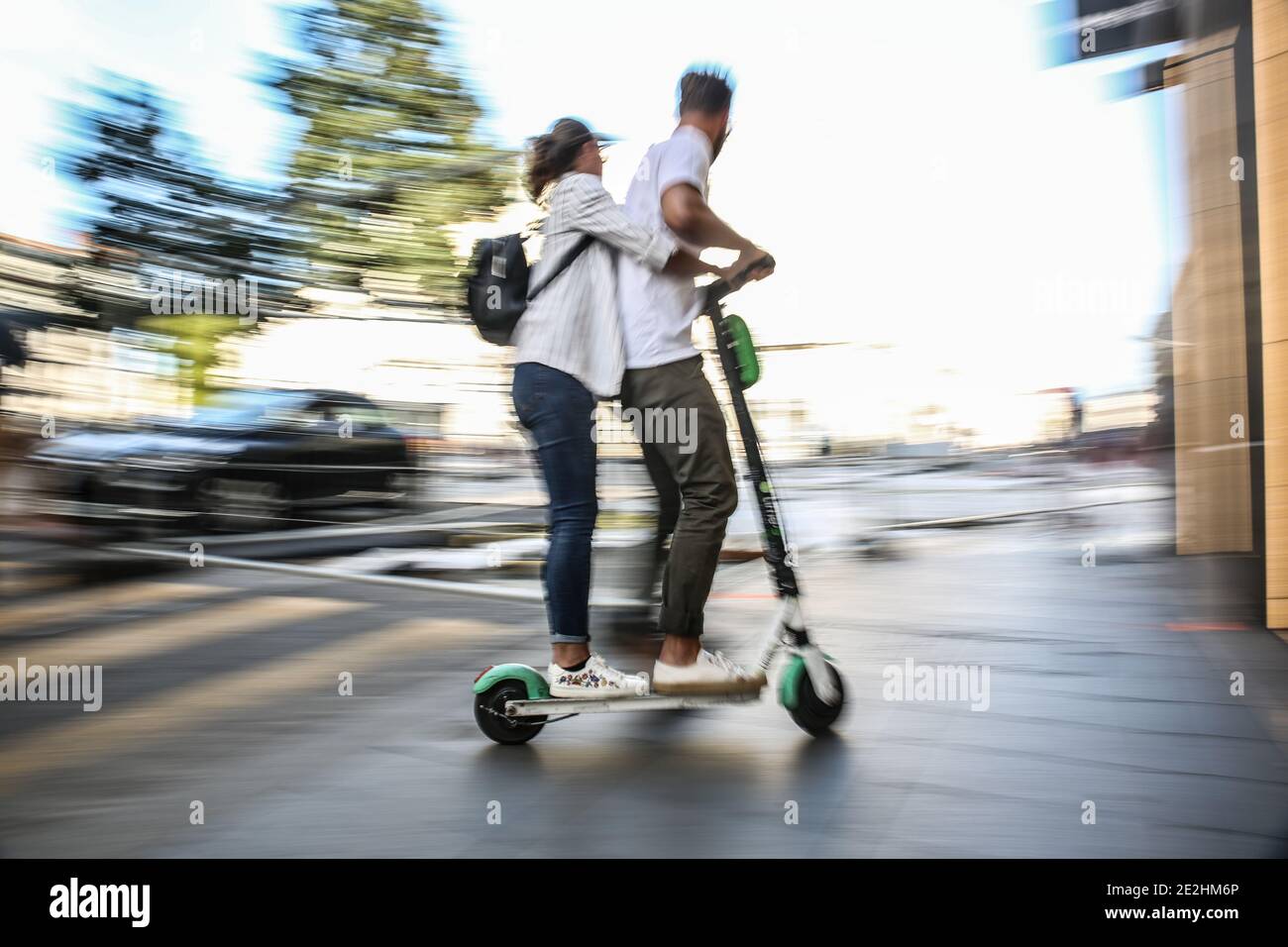 Zwei Personen, die einen Elektroroller auf einem Bürgersteig, ohne Helm, in  Lyon (Zentral-Ost-Frankreich) fahren Stockfotografie - Alamy