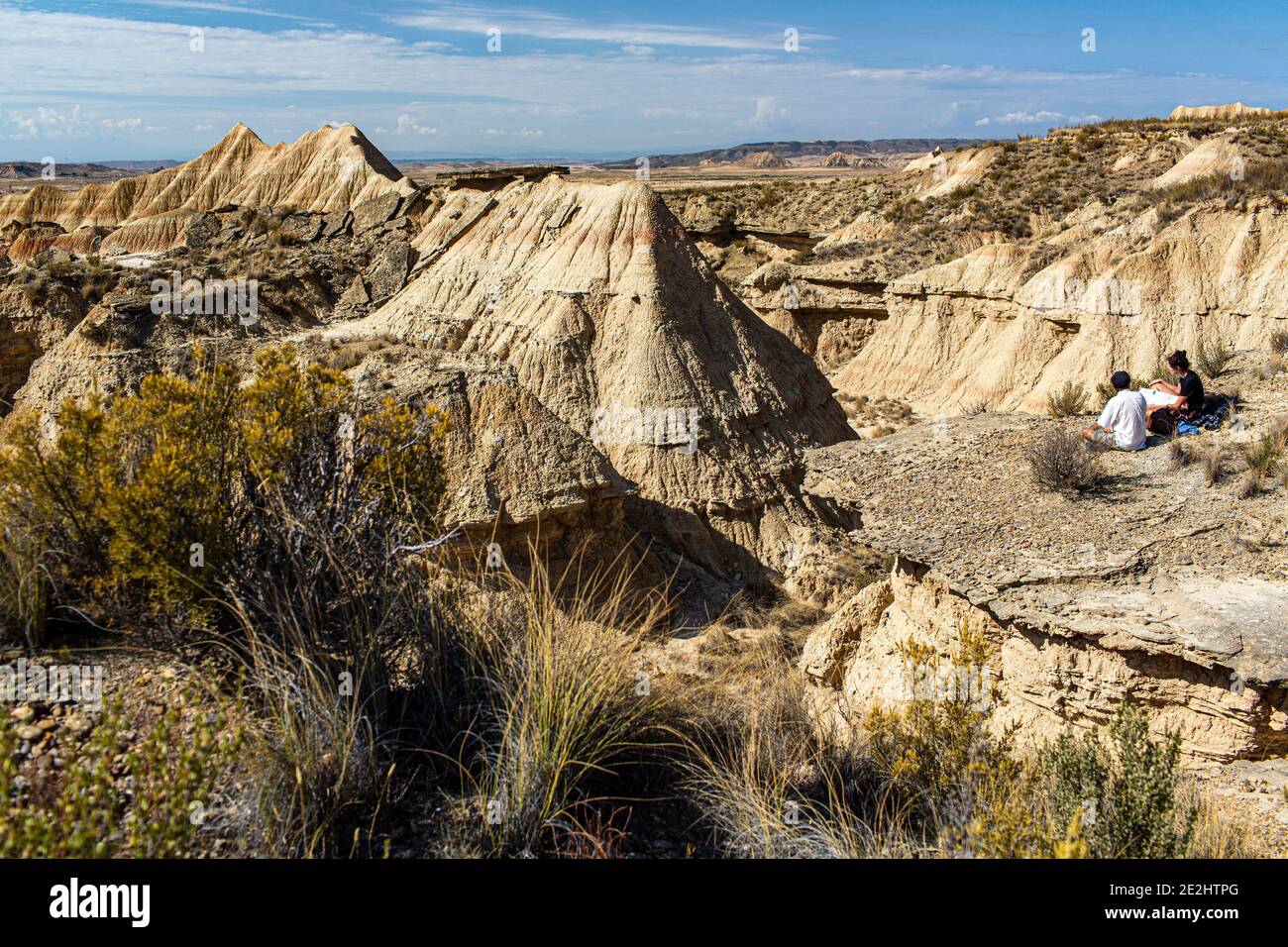 Spanien: Landschaft, Halbwüste Naturregion der Bardenas Reales, Navarra. Paar Touristen mit Blick auf die Landschaft durch Erosion gekennzeichnet. Stockfoto