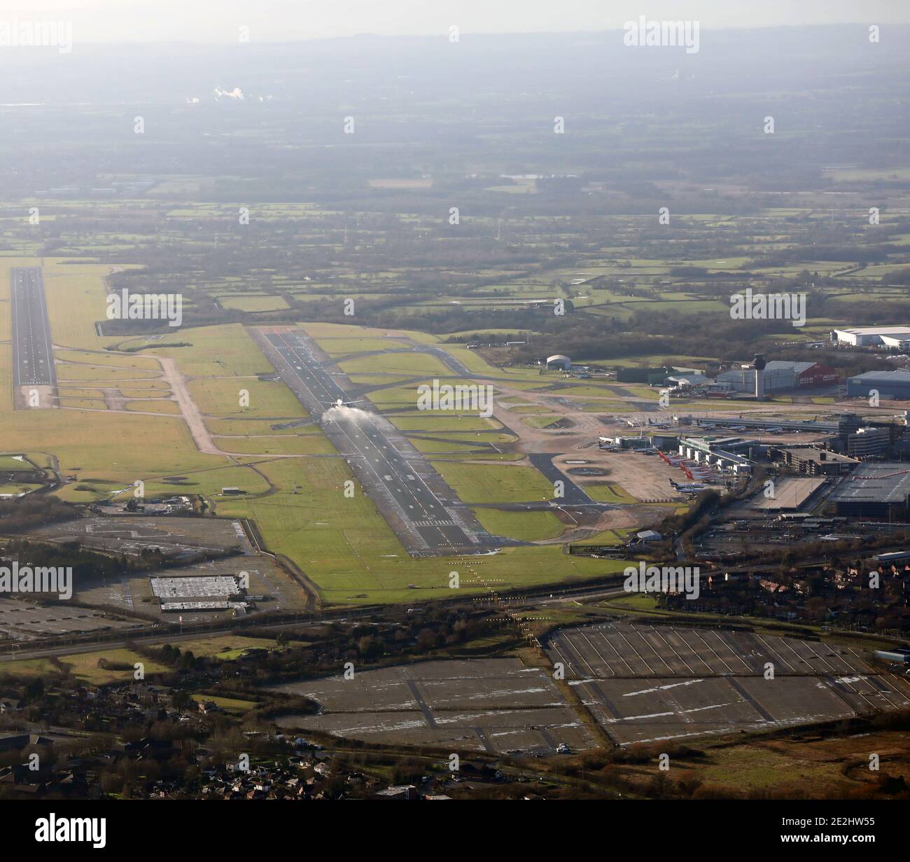 Luftaufnahme mit Blick nach Osten auf eine sehr nasse Landebahn Manchester Airport als Passagierjet hebt mit Wasser ab Spray sichtbar Stockfoto