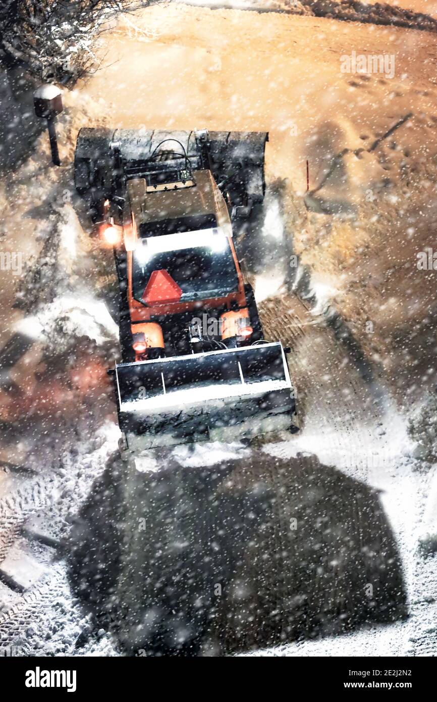 Schneetraktor bei der Arbeit Schneeräumung von Hof an einem Tag des Schneefalls, erhöhte Aussicht, keine Menschen, keine Logos. Stockfoto