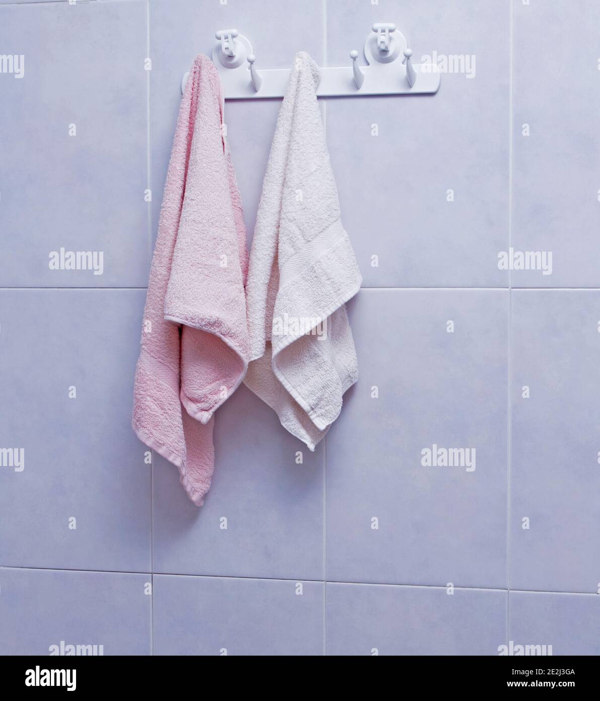Handtücher hängen auf dem gefliesten Wandhintergrund im Badezimmer Stockfoto