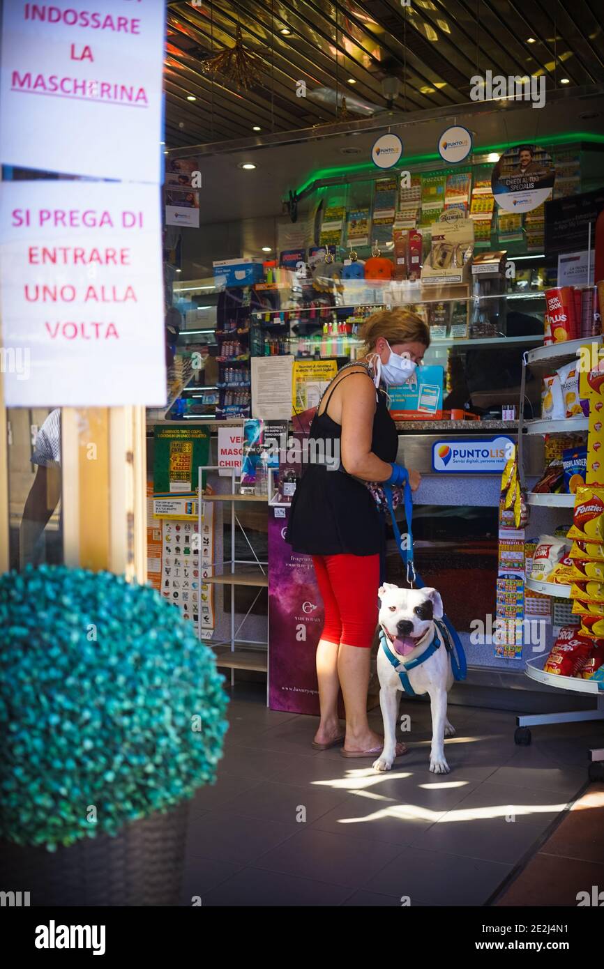 Eine Frau mit einer Maske in einem Tabakladen mit Ihr Hund Stockfoto