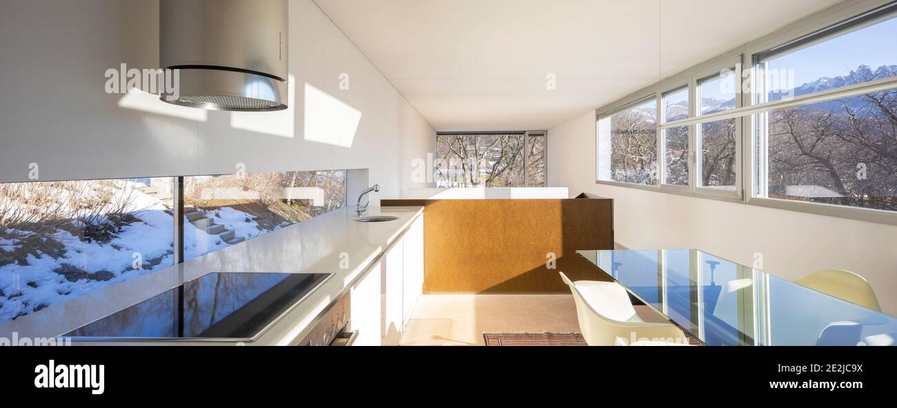 Innenansicht einer modernen Wohnung, links die Küche und rechts der Esstisch. Stockfoto