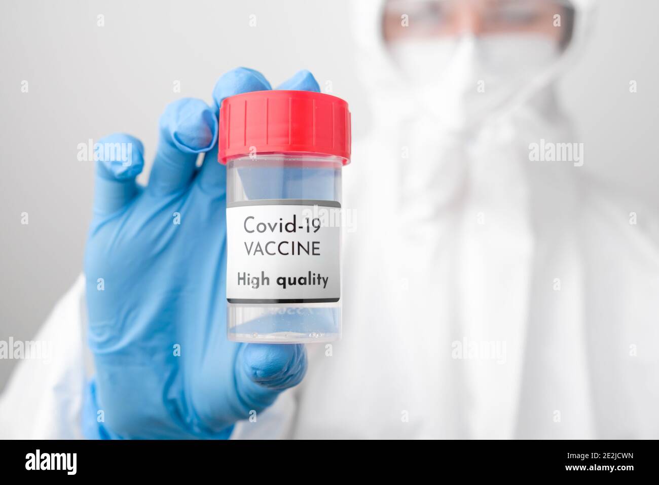 Hochwertige Covid 19 Impfstoffflasche in der Hand des Arztes. Arzt in Schutzanzug, Gesichtsmaske, Sicherheits-googles und Gummihandschuhe zeigen Impfstoff Stockfoto