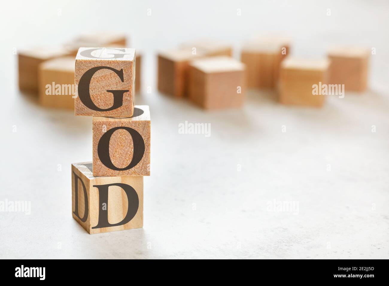 Drei Holzwürfel mit Wort GOTT, auf weißem Tisch, mehr im Hintergrund, Platz für Text in der rechten unteren Ecke Stockfoto
